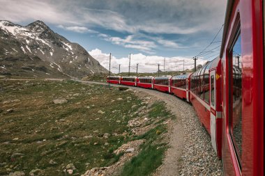 Bernina İsviçre 'de ekspres. İsviçre Alpleri 'nin simgesidir. Yazın güzel bir Alp manzarası. Dağlardaki demiryolu köprüsündeki kızıl buzullu tren. Demiryolunun manzaralı panoramik manzarası