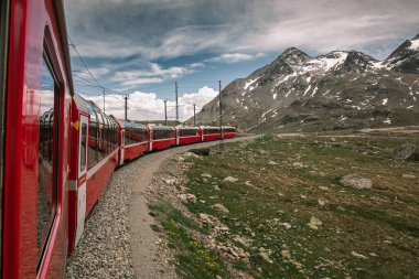 Bernina İsviçre 'de ekspres. İsviçre Alpleri 'nin simgesidir. Yazın güzel bir Alp manzarası. Dağlardaki demiryolu köprüsündeki kızıl buzullu tren. Demiryolunun manzaralı panoramik manzarası