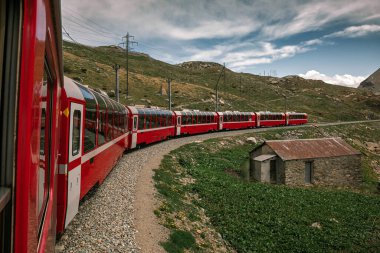 Bernina İsviçre 'de ekspres. İsviçre Alpleri 'nin simgesidir. Yazın güzel bir Alp manzarası. Dağlardaki demiryolu köprüsündeki kızıl buzullu tren. Demiryolunun manzaralı panoramik manzarası