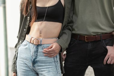 Close up portrait of couple men and woman with fashion leather belts and jeans. Casual urban style. Clothing and accessories for a man and a woman