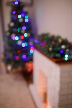 Yılbaşı ağacı ve akşam süslenmiş bir ev. Hediye kutuları ve beyaz tuğlalı şöminenin yanında kırmızı çoraplar. Konsept - Önümüzdeki 2022 Yeni Yıl. Kasıtlı olarak bulanık