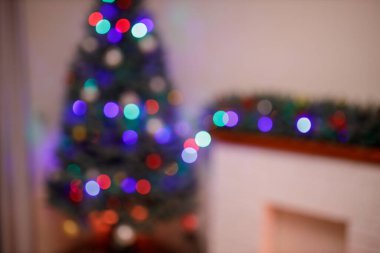 Yılbaşı ağacı ve akşam süslenmiş bir ev. Hediye kutuları ve beyaz tuğlalı şöminenin yanında kırmızı çoraplar. Konsept - Önümüzdeki 2022 Yeni Yıl. Kasıtlı olarak bulanık