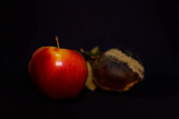 腐烂的苦瓜和新鲜的苹果在黑色表面 它已不适合人类消费 关于年轻和老年 内在美 疾病的概念性照片 Dorian Grey的想法 — 图库照片