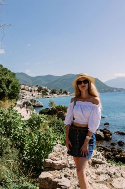 Gezinti güvertesindeki kadın, Karadağ 'ın güneybatısındaki Adriyatik Denizi yakınlarındaki Kotor Körfezi yakınlarındaki ortaçağ kasabasında poz veriyor. Seyahat ve kiralama konsepti. Dinlenme alanı
