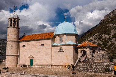 Perast, Karadağ - 15.09.2021: Roma Katolik kilisesi, Karadağ 'ın dağlık alanı ve mavi gökyüzü önündeki boka kotor körfezindeki kayalıklardaki leydimiz. Unesco Dünya Mirası.