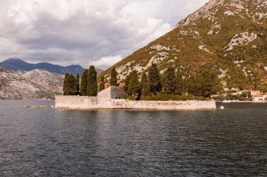 Karadağ 'ın Perast kenti yakınlarındaki Kotor Körfezi' ndeki (Boka Kotorska) Saint George Adası 'nın açık hava manzarası, güneşli bir günde deniz kıyısı ve mavi gökyüzü. Unesco 'nun dünya mirası. Avrupa seyahat alanı. Tatil kavramı