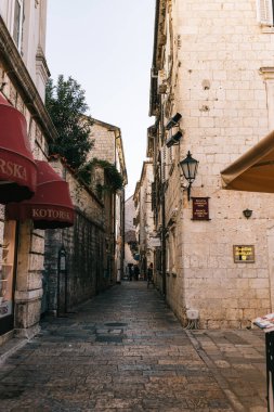 Kotor, Karadağ - 15.09.2021: Eski dar sokak. Taş duvarlar ve saksıları olan kapı. Otantik ortaçağ taş kiremitleri. Avrupa 'da seyahat ve turizm kavramı. Turizm ve seyahat kavramı