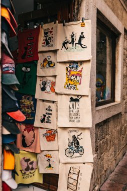 Kotor, Karadağ - 15.09.2021: çeşitli çantalar ve satılık diğer eşyalarla hediyelik eşya dükkanı. Kediler resimlerle ilgili - eski antik şehrin sembolü