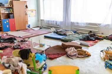 Barmashovo, Ukrayna... 18 Mart 2022, Rus işgalinden sonra yarı yıkılmış okul odasında paspas ve çöp. İnsanlar onlara 