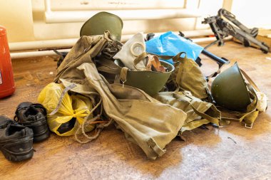 Barmashovo, Ukrayna... 18 Mart 2022: Rus işgalinden sonra yarı tahrip olmuş okul salonunda askeri miğferler, silah ve gaz maskeleri. İnsanlar onlara 