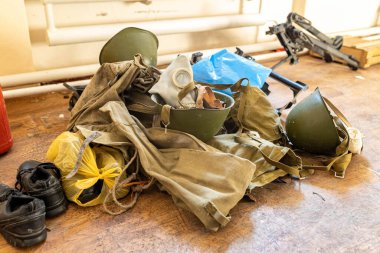Barmashovo, Ukrayna... 18 Mart 2022: Rus işgalinden sonra yarı tahrip olmuş okul salonunda askeri miğferler, silah ve gaz maskeleri. İnsanlar onlara 