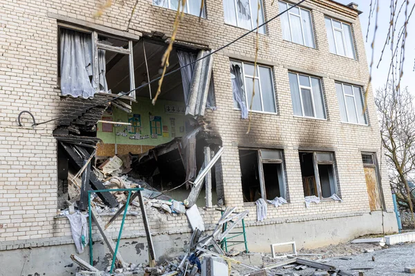 Barmashovo, Ukrayna... 18 Mart 2022 Ukrayna 'ya karşı Rusya Savaşı. İstila kavramı. Bir köyün merkezinde yakılmış ve hasar görmüş bir okul. Bomba patlamasından sonra duvardaki delikler. Kırık pencereler.