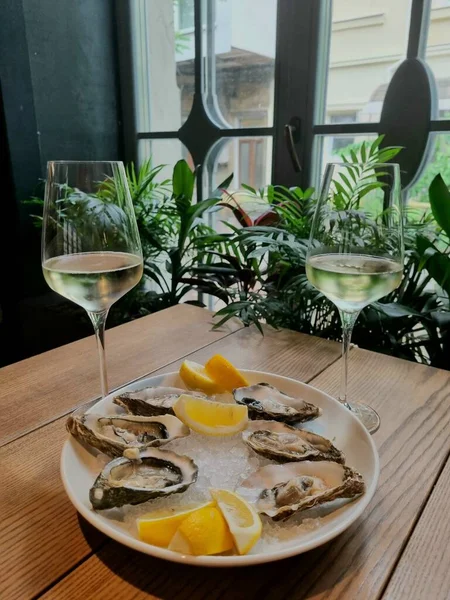 Restoranda, buzlu limonlu istiridye deniz ürünleri testi. İki kadeh beyaz şarapla romantik. 