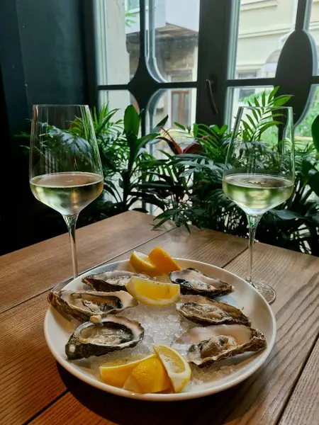 Restoranda, buzlu limonlu istiridye deniz ürünleri testi. İki kadeh beyaz şarapla romantik. 