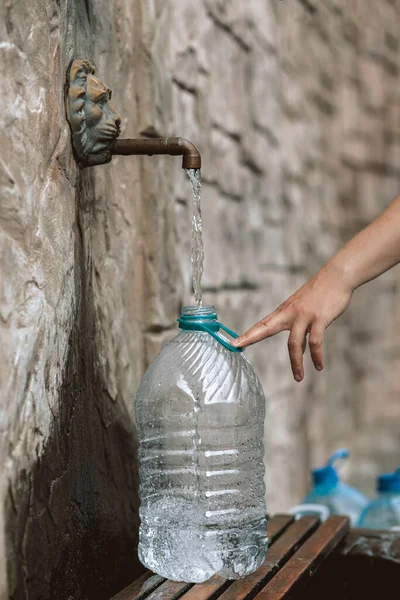 Man pour fresh spring water into plastic bottle from a natural source. Deficit, crisis, shortage of drinking water is a problem in Ukraine. Conceptual photo. Water consumption and reservation concept