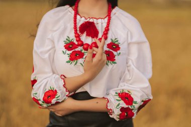 Genç kız gün batımında sarı ışıkta Ukrayna ulusal nakış işlemeli gömlek ve çiçeklerle buğday tarlasında dikiliyor. Bağımsızlık kavramı, Ukrayna 'nın özgürlüğü ve savaşı durdurmak.