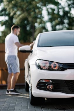 Man is wiping the car with a microfiber cloth. Contactless self-service car wash. Personal car care cleaning outside. Concept disinfection and antiseptic cleaning of vehicle, covid-19 and coronavirus