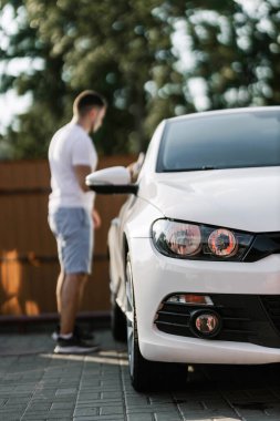 Man is wiping the car with a microfiber cloth. Contactless self-service car wash. Personal car care cleaning outside. Concept disinfection and antiseptic cleaning of vehicle, covid-19 and coronavirus