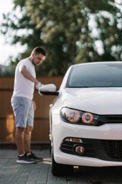 Man is wiping the car with a microfiber cloth. Contactless self-service car wash. Personal car care cleaning outside. Concept disinfection and antiseptic cleaning of vehicle, covid-19 and coronavirus