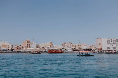 Dubai, BAE - 15 Nisan 2021 Dubai Creek kanalı manzaralı eski ahşap tekneler ve rıhtımlar. Güneşli bir yaz günü. BAE, Birleşik Arap Emirlikleri 'ndeki ünlü turizm merkezi. Abra