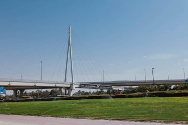 Dubai, BAE - 15 Nisan 2021: Yaz mevsiminde Dubai 'deki Naif Alradjhi Yatırım' a giden yol köprüsü. Sokak manzarası dışarıda. Dubai 'nin ünlü modern mimarisi bulutlu mavi gökyüzünde 