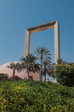  Dubai Frame altın kule binası gün batımında. Dubai 'nin bulutlu mavi gökyüzü arka planındaki ünlü modern mimarisi. Zabeel Park 'ın mimari simgesi. Gezegendeki en büyük altın çerçeve