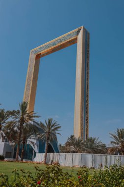  Dubai Frame altın kule binası gün batımında. Dubai 'nin bulutlu mavi gökyüzü arka planındaki ünlü modern mimarisi. Zabeel Park 'ın mimari simgesi. Gezegendeki en büyük altın çerçeve