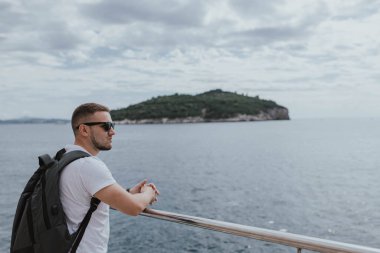 Adam, Adriyatik Denizi 'ndeki Lokrum Adası takımadalarının Dalmaçya' nın antik Hırvat kenti Dubrovnik 'teki manzarasına bakıyor. Seyahat ve doğa kavramı. uçurum ve sahil, mavi deniz ve dağ