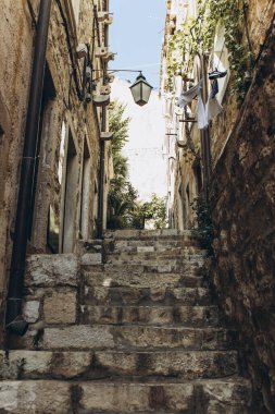 Dubrovnik, Hırvatistan - 21 Eylül 2021: Eski ortaçağ kasabasında yeşillik bulunan dar karanlık sokak, UNESCO Dünya Mirası Listesi 'ne eklendi. Kralın Şehri, Yedi Krallık 'ın başkenti Game of Thrones' da