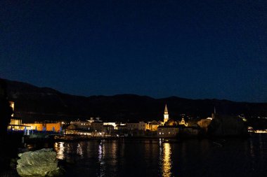BUDVA, MONTENEGRO - 21 Eylül 2021: Gece eski Budva kasabası manzarası. Adriyatik Denizi. Sahil şeridi manzarası. Su üzerinde güzel ışık yansımaları