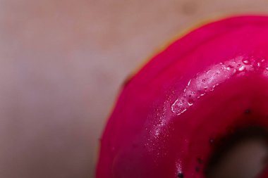 Donutun Pembe Buzlu Tam Yakın Çekimi. Üst Manzara. Lezzetli, yağlı, yüksek kalorili tatlı yiyecekler. Seçici Odaklanma. En sevdiğim çocukluk hediyesi. Makro. Doğum günü kutlamaları için bir damla su.