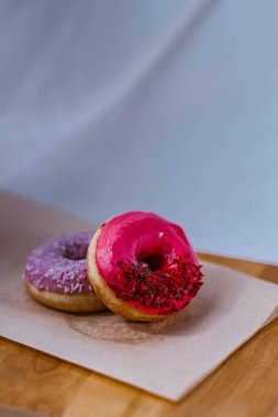 Pembe ve mor buzlu donutların ve haşhaş tohumlu renkli serpintilerin tam yakın çekimi. Yan Görünüm. Lezzetli, yağlı, yüksek kalorili tatlı yiyecekler. Seçici Odaklanma. favori çocukluk hediyesi