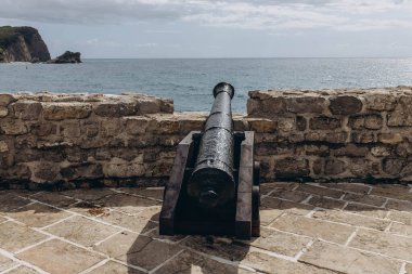Budva, Karadağ - 18 Eylül 2021: Eski taştan kale üzerindeki eski bir top UNESCO Dünya Mirasları Listesi 'nde yer aldı. Turizm ve seyahat konsepti. Avrupalı turistlerin cazibesi