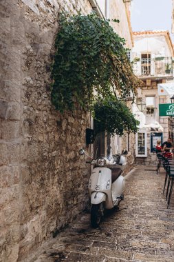 Budva, Karadağ - 18 Eylül 2021: kalede UNESCO Dünya Mirasları listesinde yer alan retro motosiklet scooter 'ı. Kafenin girişi. Seyahat konsepti. Çekici Avrupalı, dünya çapında turistler
