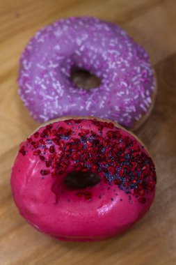 Pembe ve menekşe aromalı çörekler ve ahşap zemin üzerinde haşhaş tohumu ve kuru ahududu olan renkli serpintiler. Lezzetli, yağlı, yüksek kalorili tatlı yiyecekler. Seçici Odaklanma. favori çocukluk hediyesi