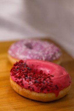 Pembe ve menekşe aromalı çörekler ve ahşap zemin üzerinde haşhaş tohumu ve kuru ahududu olan renkli serpintiler. Lezzetli, yağlı, yüksek kalorili tatlı yiyecekler. Seçici Odaklanma. favori çocukluk hediyesi