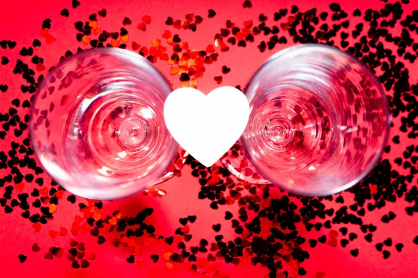 Copas de champán, corazones de madera y confeti rojo. — Foto de Stock