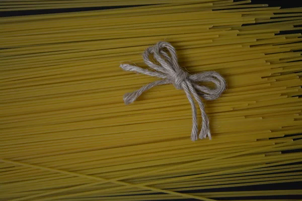 Rå spagetti pakket inn i tau på svart bakgrunn, lukket – stockfoto