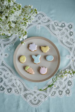 Paskalya kompozisyonu, beyaz plakalı yumurtalar. Paskalya yumurtaları ve bahar çiçekleriyle paskalya arkaplanı. Zencefilli kurabiye Yumurta şeklinde kurabiyeler ve Paskalya tavşanı.