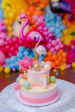 Küçük bir kızın doğum günü için üstünde yenilebilir pembe flamingo figürü olan doğum günü pastası. Şeker çubuğu.