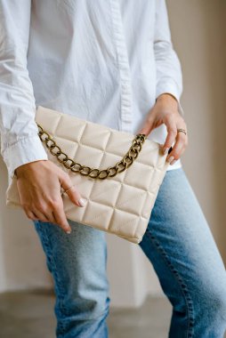 Siyah çantalı şık bir kadın. Omzunda torba olan bir kız. Omuz çantaları kadınlar için. Moda görünümlü kadın kıyafeti. Havalı kadınların bej çantaları. Yakın plan..