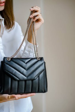 Siyah çantalı şık bir kadın. Omzunda torba olan bir kız. Omuz çantaları kadınlar için. Moda görünümlü kadın kıyafeti. Havalı kadınların bej çantaları. Yakın plan..