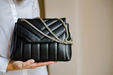 Siyah çantalı şık bir kadın. Omzunda torba olan bir kız. Omuz çantaları kadınlar için. Moda görünümlü kadın kıyafeti. Havalı kadınların bej çantaları. Yakın plan..