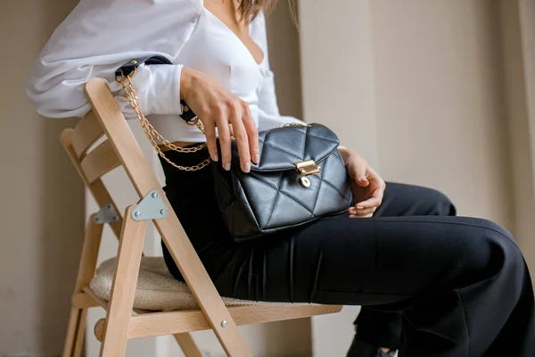 Trendy outfit woman with black bag. Girl with bag over his shoulder  outdoors. Shoulder Bags for Women. Fashion look woman outfit. Stylish  women's beige handbag. Close-up. Stock Photo