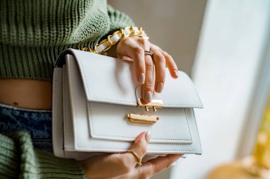 Siyah çantalı şık bir kadın. Omzunda torba olan bir kız. Omuz çantaları kadınlar için. Moda görünümlü kadın kıyafeti. Havalı kadınların bej çantaları. Yakın plan..