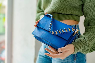 Siyah çantalı şık bir kadın. Omzunda torba olan bir kız. Omuz çantaları kadınlar için. Moda görünümlü kadın kıyafeti. Havalı kadınların bej çantaları. Yakın plan..