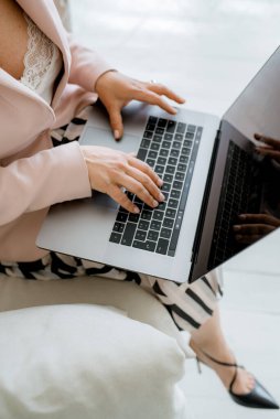 Çalışan genç iş kadını dizüstü bilgisayarla oturuyor.