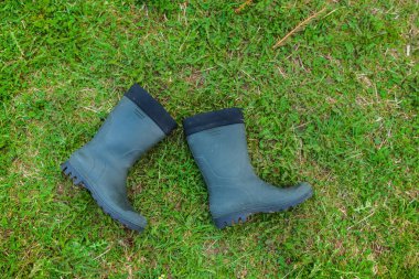 Yeşil çimlerde lastik çizmeler