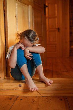 Baby is sad at home. A little girl cries sadly hiding at home. The child is upset and crying. The little girl covered her face with her hands.