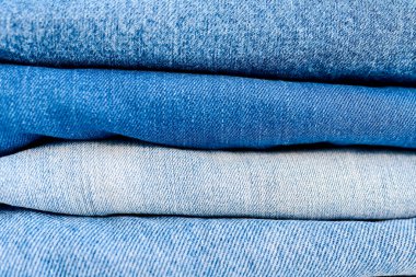 Gri duvar arkaplanını kapatan katlanmış kot pantolon yığınını kopyala